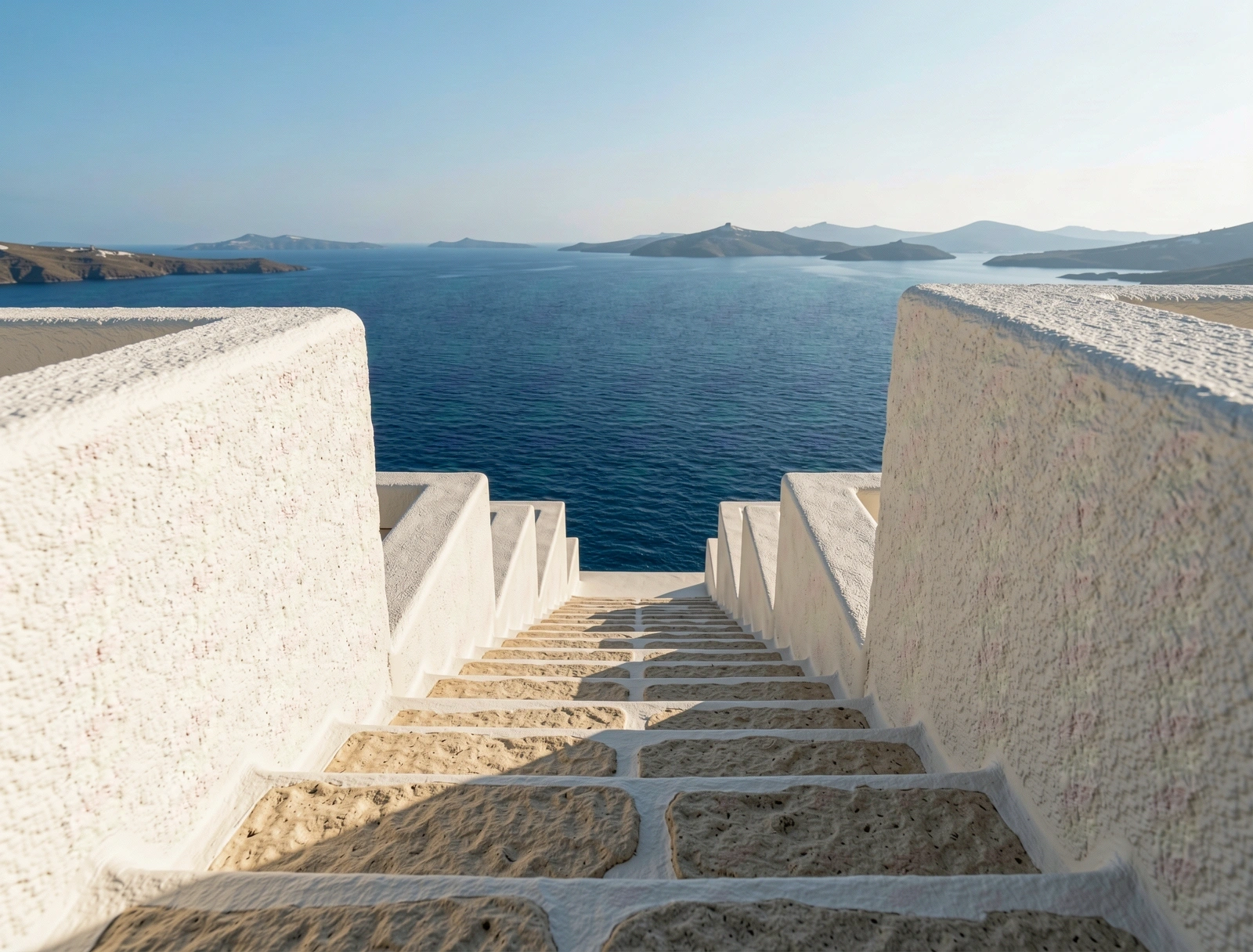 Whitewashed stone stairs overlooking the turquoise Aegean Sea